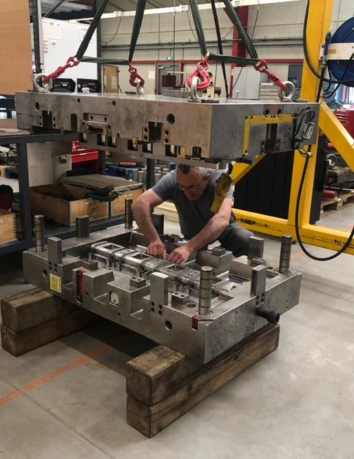 Ouvrier assemblant un moule industriel lourd suspendu par une grue à Salbris dans le Loir-et-Cher 41