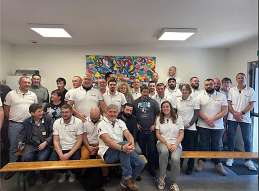 Groupe diversifié d'hommes et de femmes souriants en polos blancs posant pour une photo.
