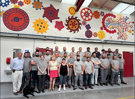 Un grand groupe de travailleurs et un chien posent devant une fresque murale à Salbris dans le Loir-et-Cher 41